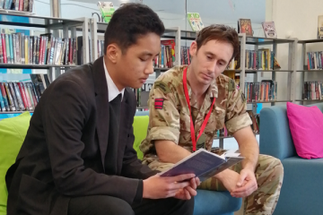 Soldier and student reading together
